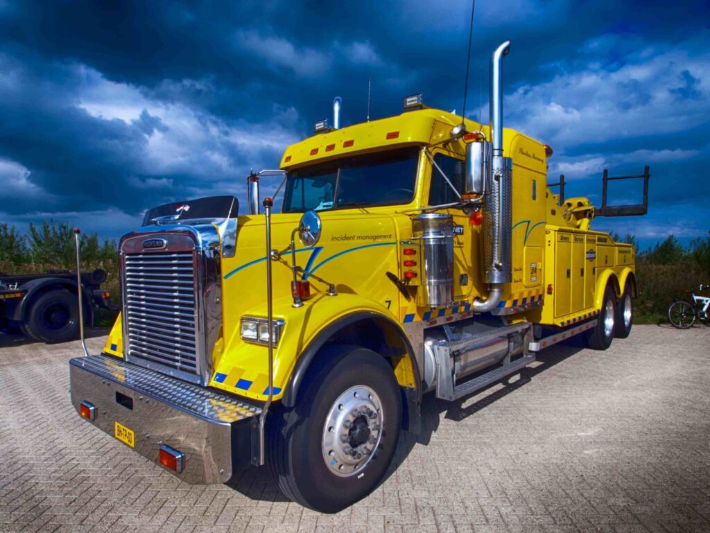 Yellow semi-truck parked under a cloudy sky offering 24/7 Emergency Roadside Assistance in Delhi, LA.