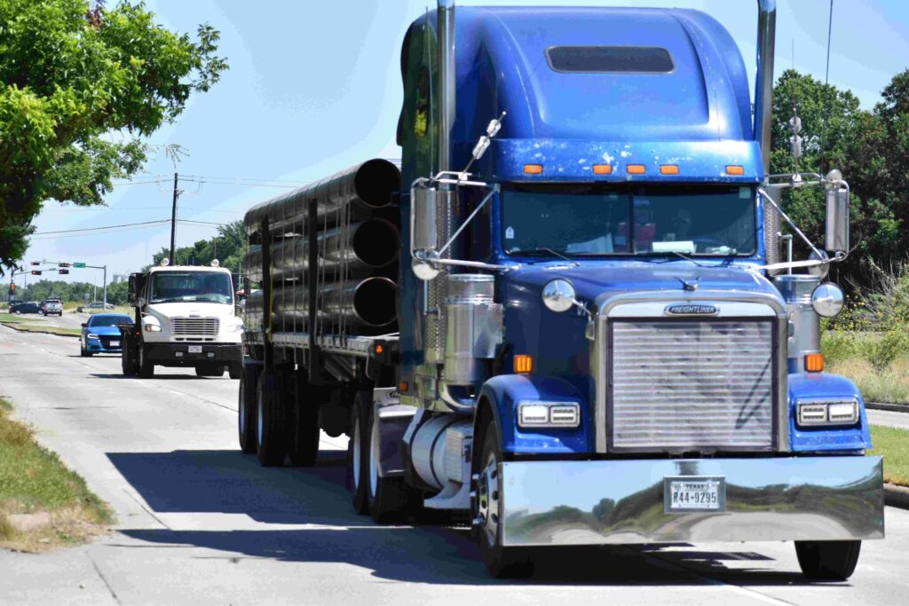 Two semi-trucks driving on a road with other vehicles in the background.
